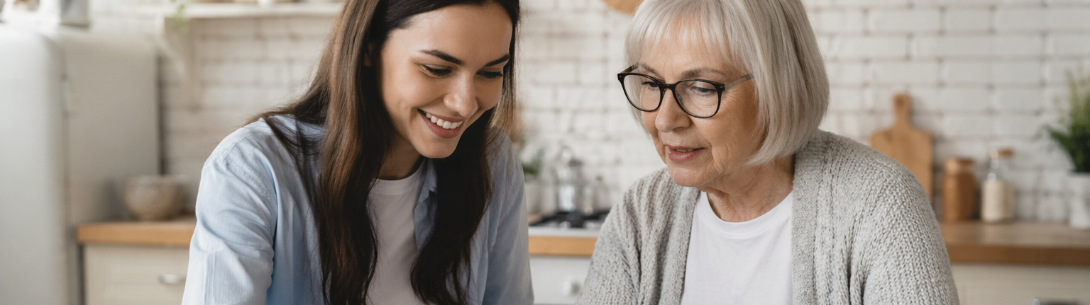 Eine junge Frau hilft einer älteren Frau am Laptop