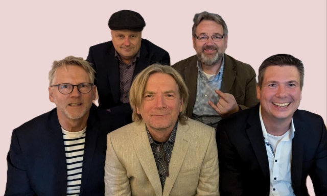 Die Mitglieder der Band sitzen nebeneinander